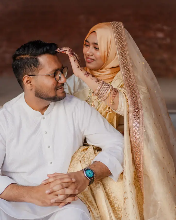 Anika adjusts Faisal’s hair on the steps of an old red-brick building
