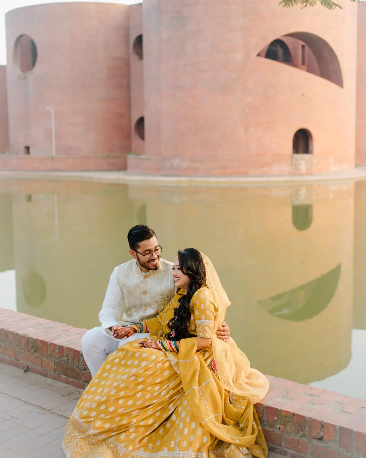 Anika in a yellow lehenga beside Faisal at the edge of a still pool