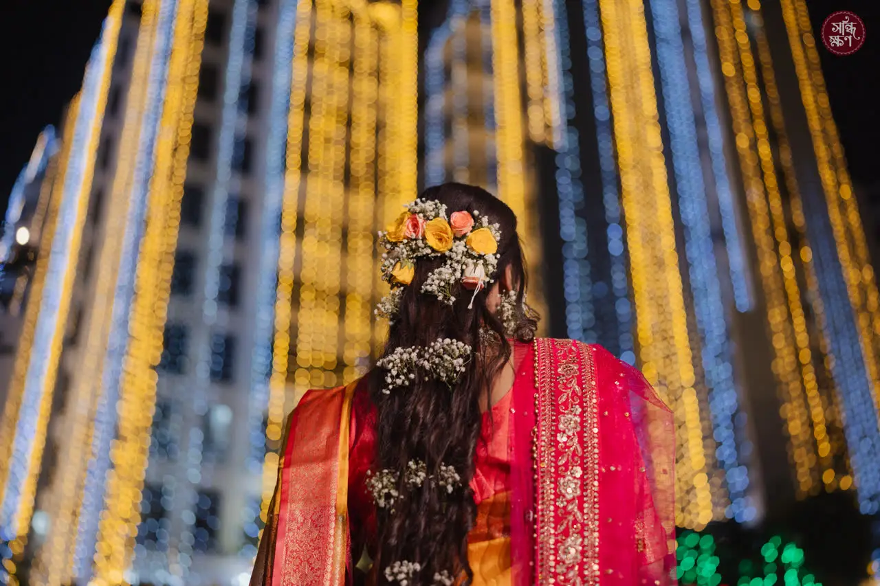 Flowers pinned in Anika’s braid against strings of festival lights