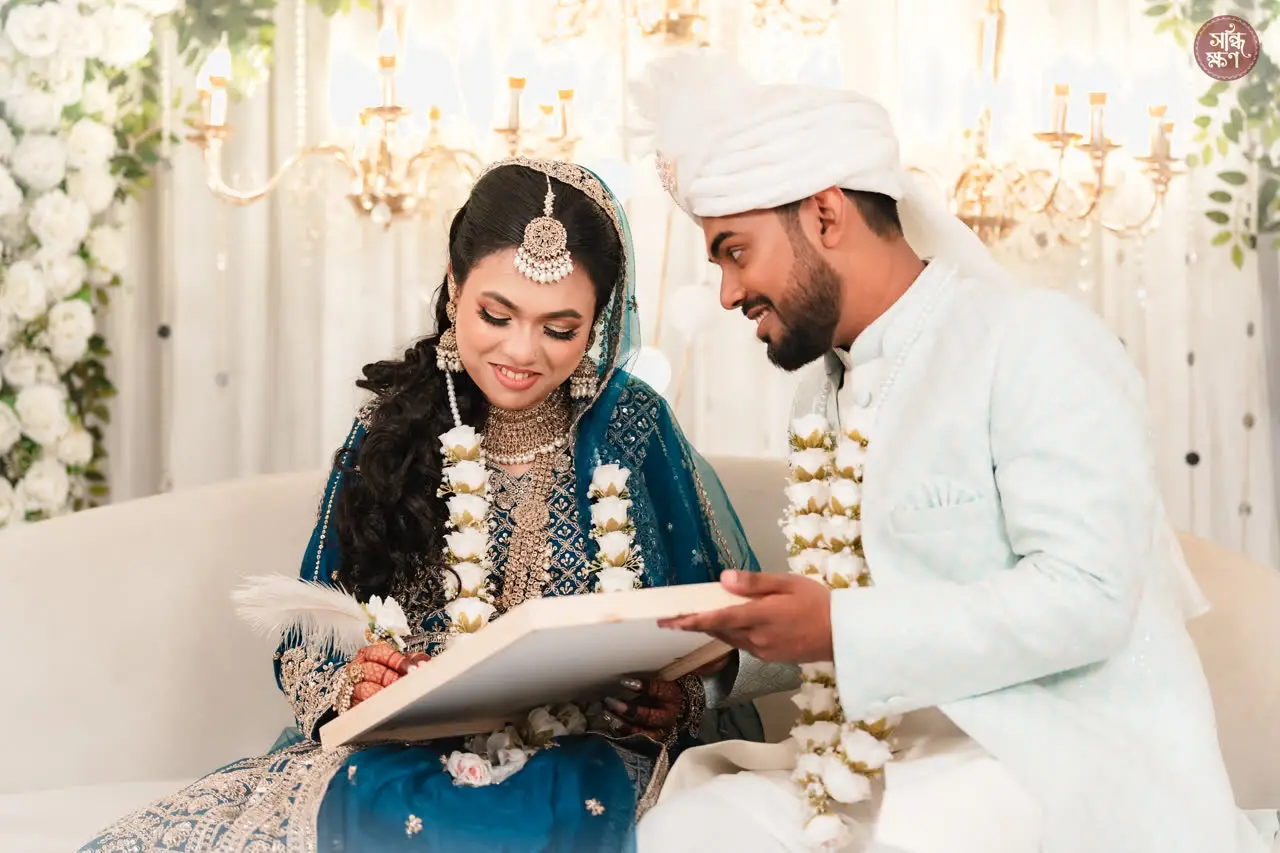 Faisal and Anika signing the marriage register, garlands around their necks