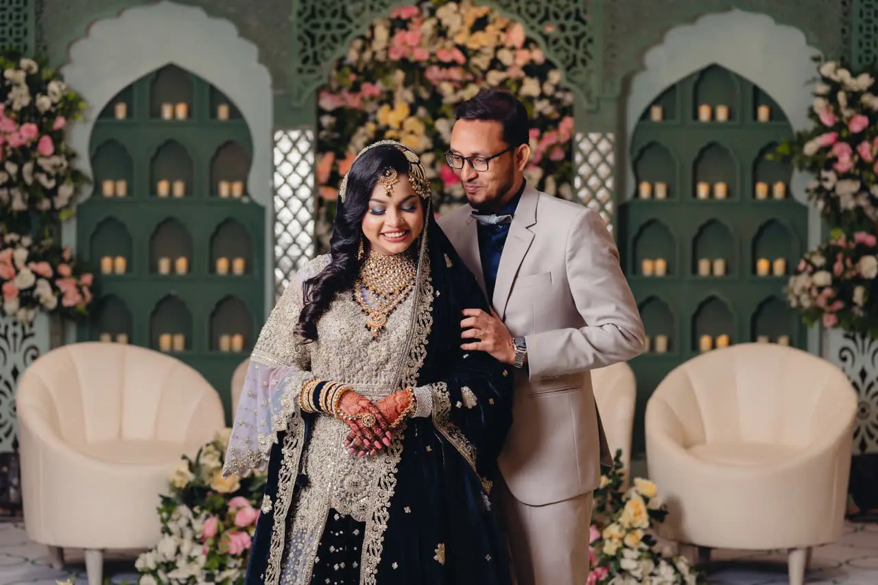Anika and Faisal standing together on a floral reception stage