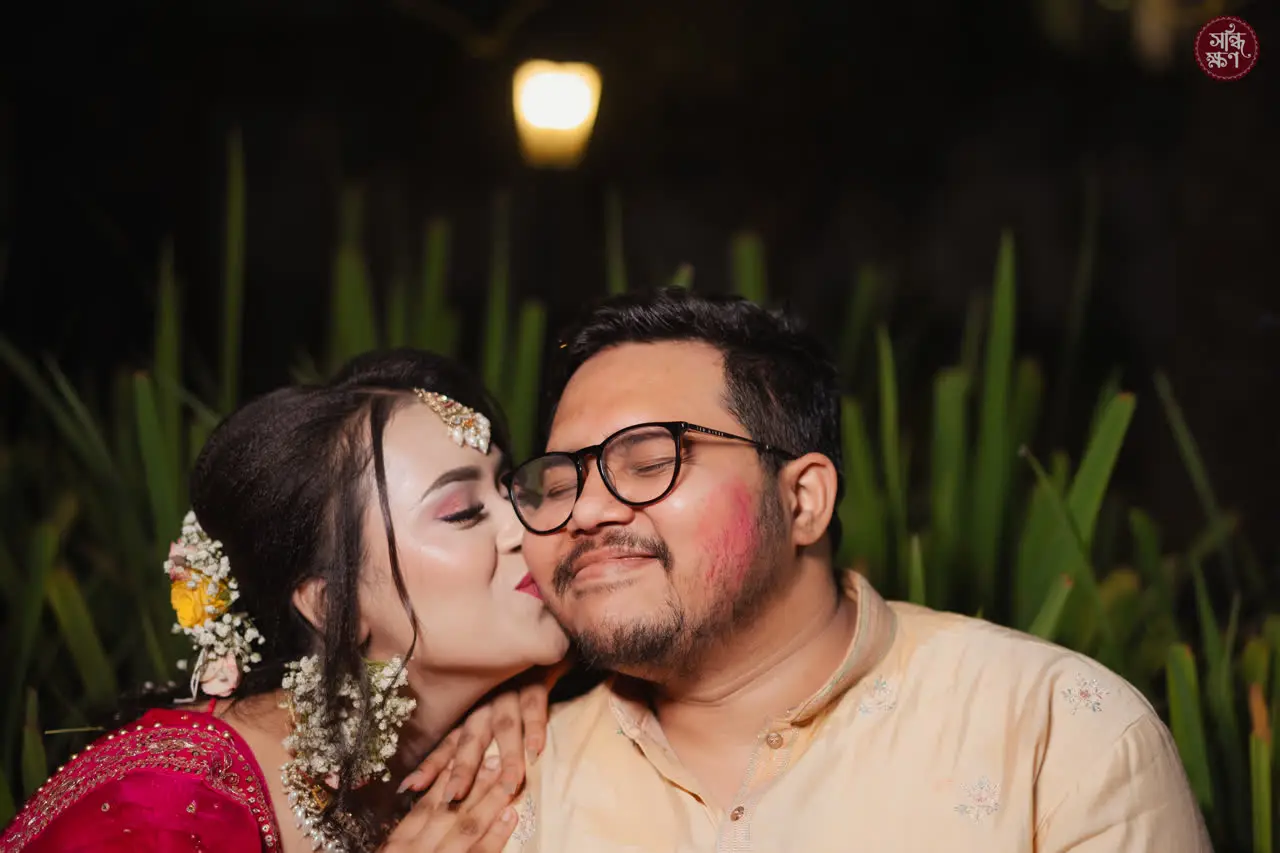 Anika kisses Faisal on the cheek; he laughs behind his glasses