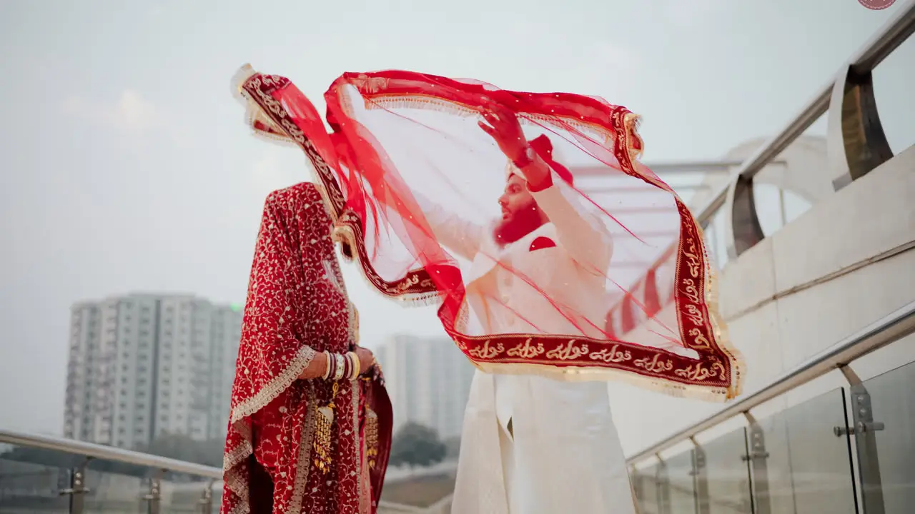 Film still: Nadia’s red veil caught by the wind on a rooftop
