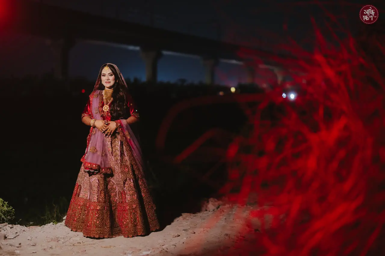 Nadia standing alone at night, red light spilling across the frame