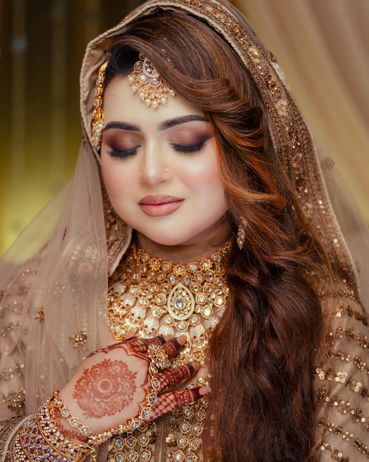 Nadia looks down at her hennaed hands, gold jewellery catching the light