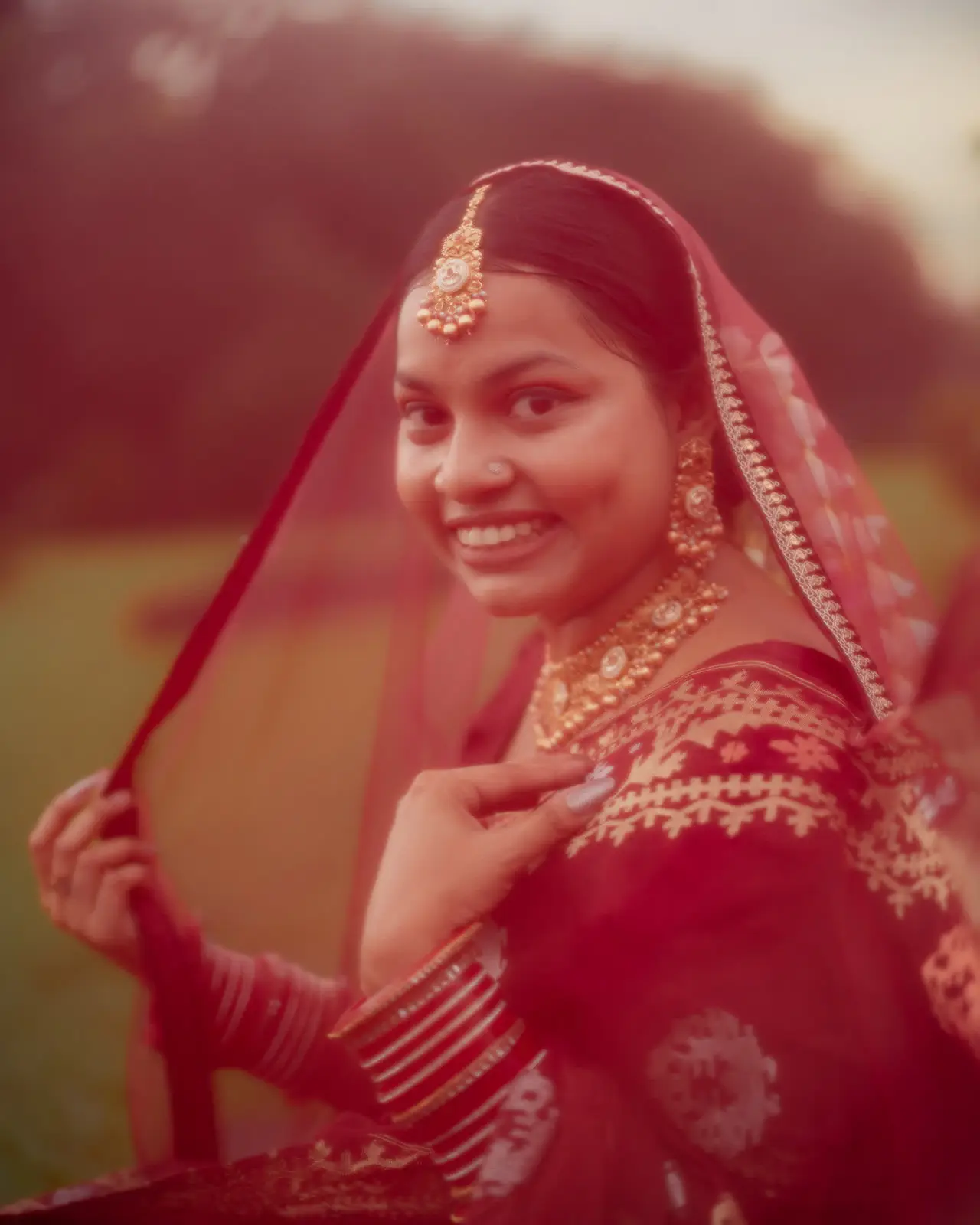 Sarah smiles through a red veil