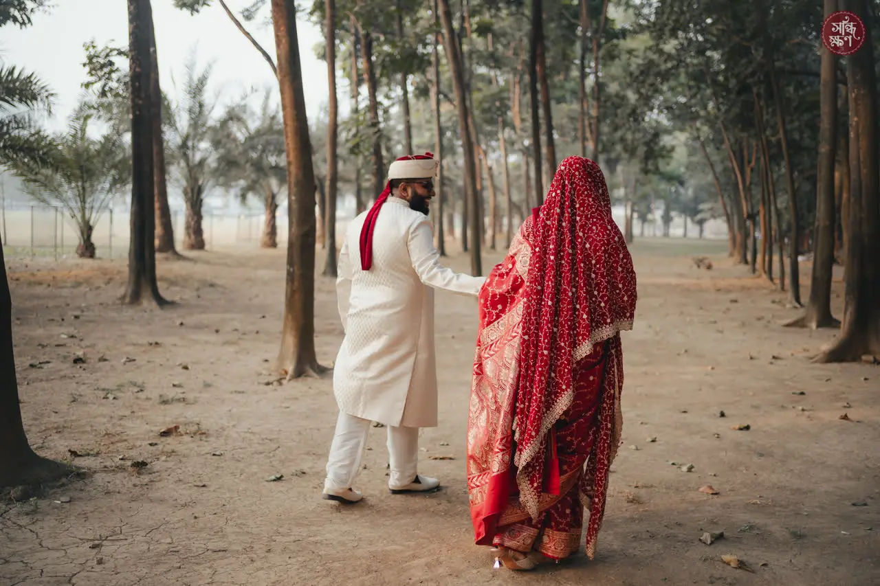 Rahim and Sarah walk away between tall trees