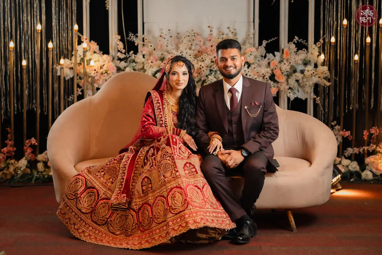 Rahim and Sarah on a curved sofa surrounded by lights and flowers
